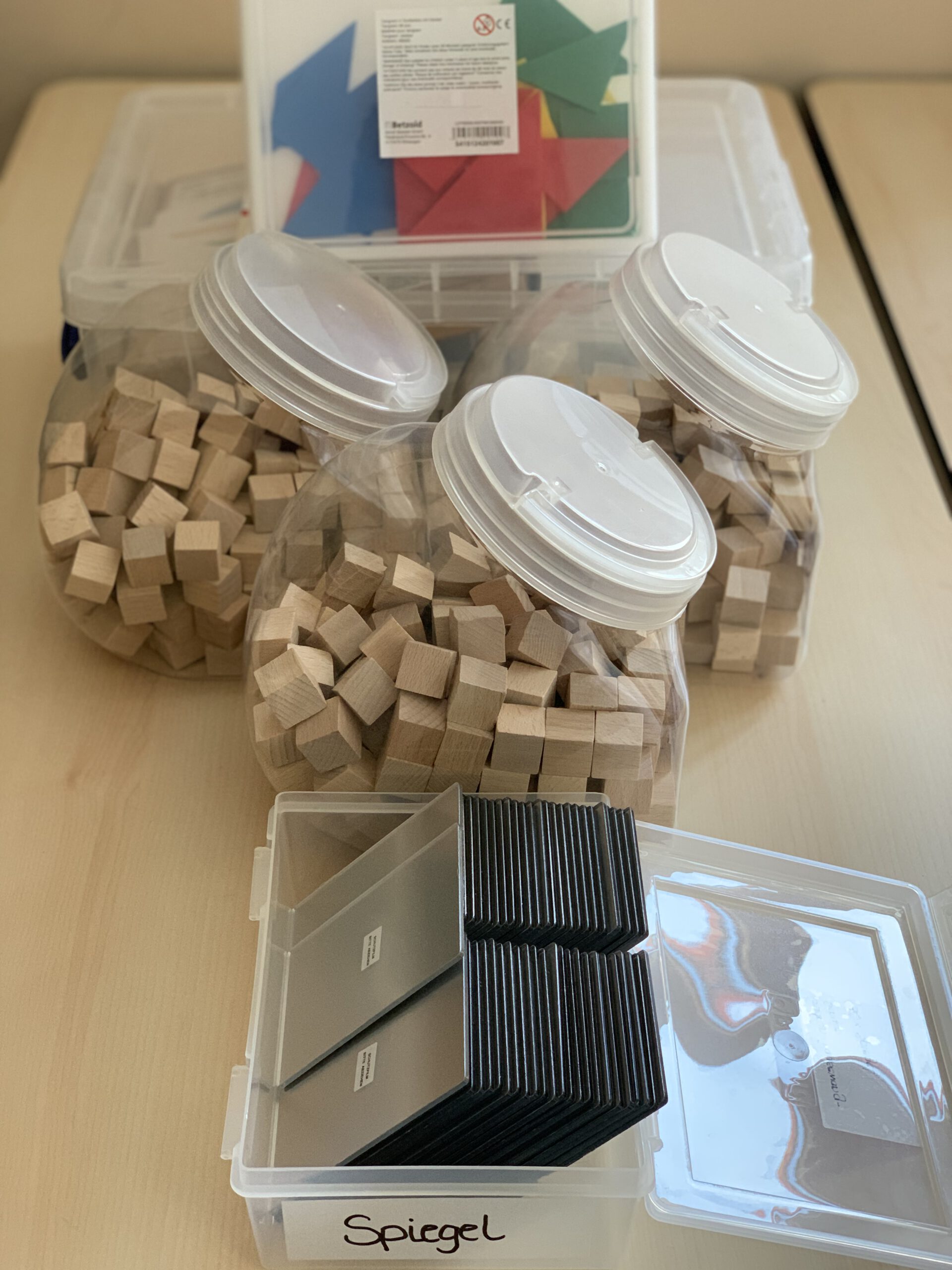 Lernmaterialien wie Holzwürfel, Tangram und Spiegel