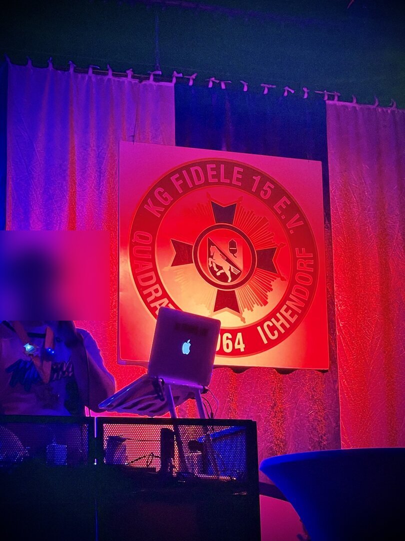 DJ vor dem Wappen der KG Fidele 15 Quadrath-Ichendorf